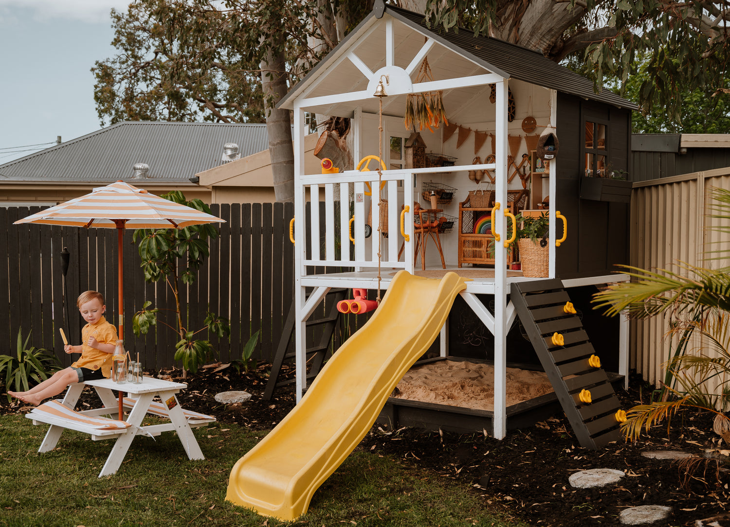 My Kidz Shack Cubby House in backyard play setup, featuring slide and open verandah by Hide & Seek Kids