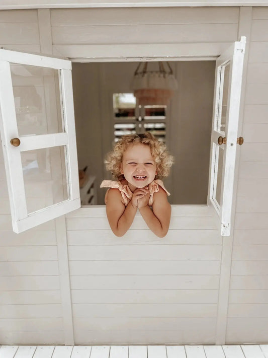 The Ultimate Cubby House Safety Checklist for Australian Parents - Hide and Seek Kids - Little Girl looking out cubby house window