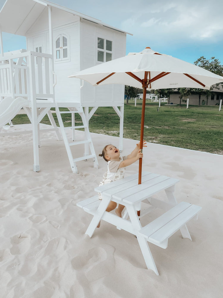 White wooden Marlie Cubby playhouse with pitched roof and window openings, designed for children's indoor or outdoor play