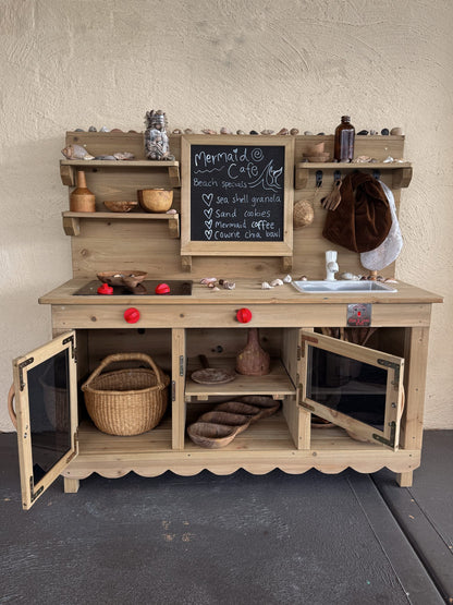 Mud Kitchen Molly by Hide and Seek Kids showing plumbable sink with tap and open shelving in backyard setting