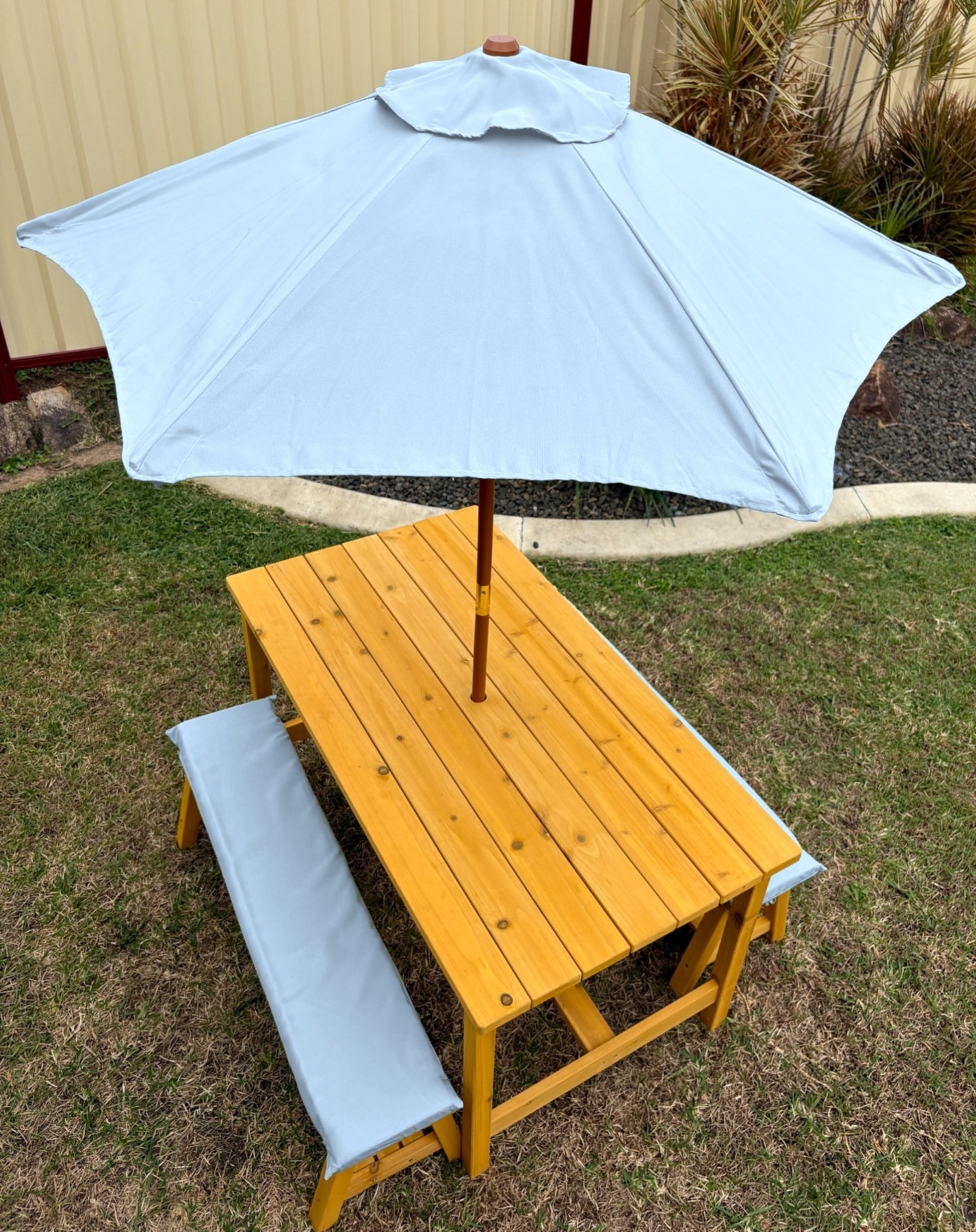 Kids timber picnic table and bench set with umbrella and cushions in baby blue outdoor setting