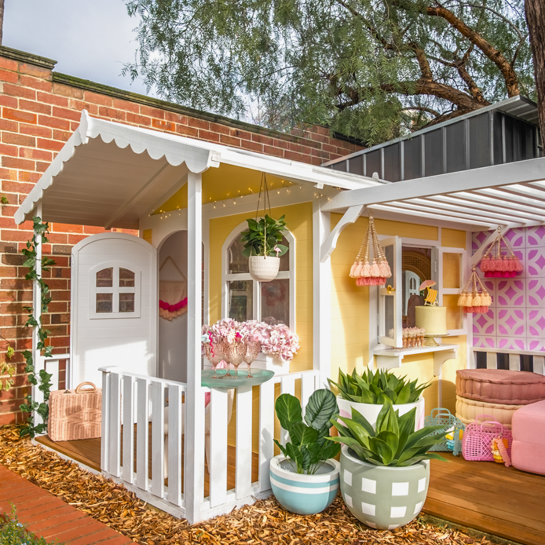 Billie Grand Cubby House by Hide & Seek Kids – yellow painted timber cubby with veranda and the Pergola Add-on installed.