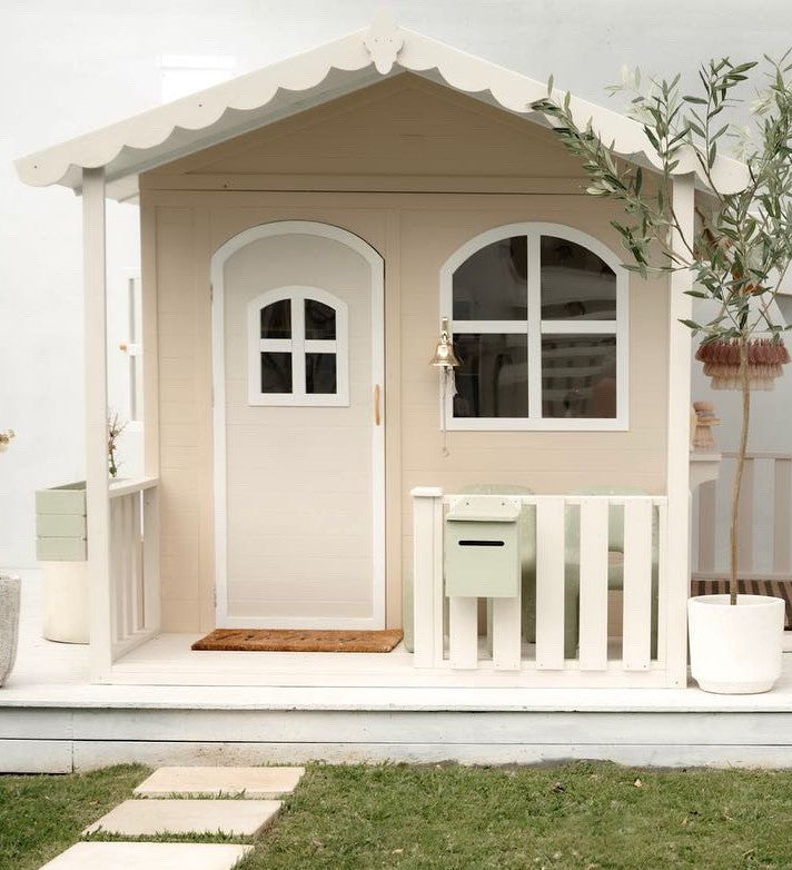 Billie Grand Cubby House by Hide & Seek Kids – cream painted timber cubby with veranda and large arched front windows with the Cottage Fascia Add-On installed.