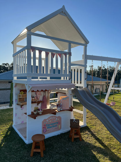 The Rusty Fort by Hide & Seek Kids in a backyard setting with slide and cafe shop setup on grass