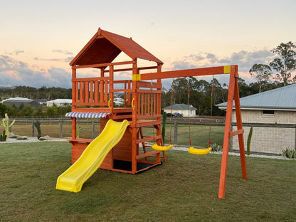 Front side view of The Rusty Fort with yellow wavy slide, double swings, and café-style front window