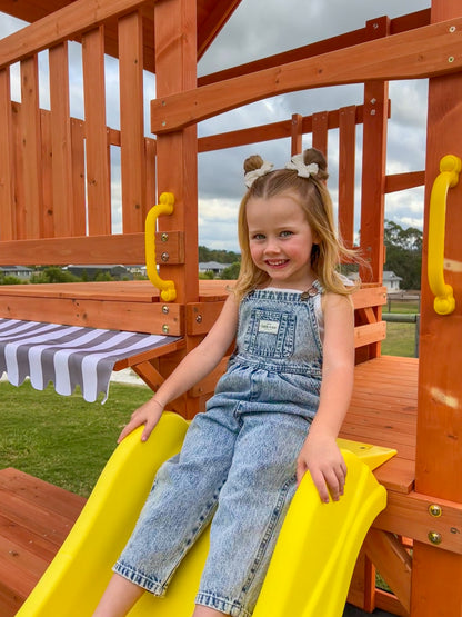 Young girl playing on The Rusty Fort slide, close up of timber finish and coloured handles.